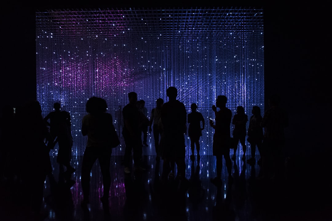A group of professionals standing in an area with a large, bright, futuristic digital networking map display A group of professionals standing in an area with a large, bright, futuristic digital networking map display
