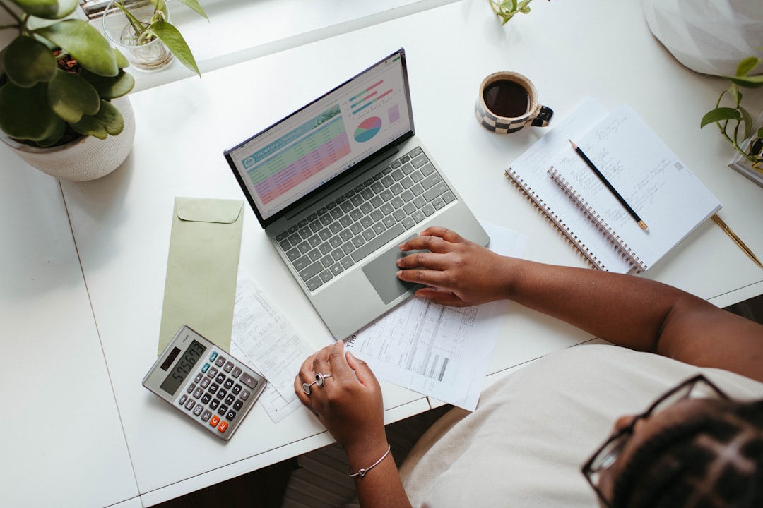 A professional accountant looking at a laptop screen filled with financial charts and tax calculation documents. A professional accountant looking at a laptop screen filled with financial charts and tax calculation documents.